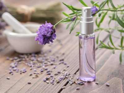 intégrer une eau florale à sa routine beauté - photo d'un flacon violet posé sur une table en bois avec des plantes.