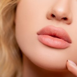 demi-visage du femme blonde avec son nez sa bouche et deux doigts